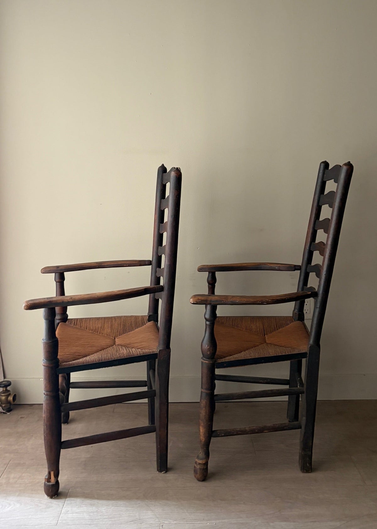 English provincial elmwood ladder back rush seat armchairs. Sold individually.
