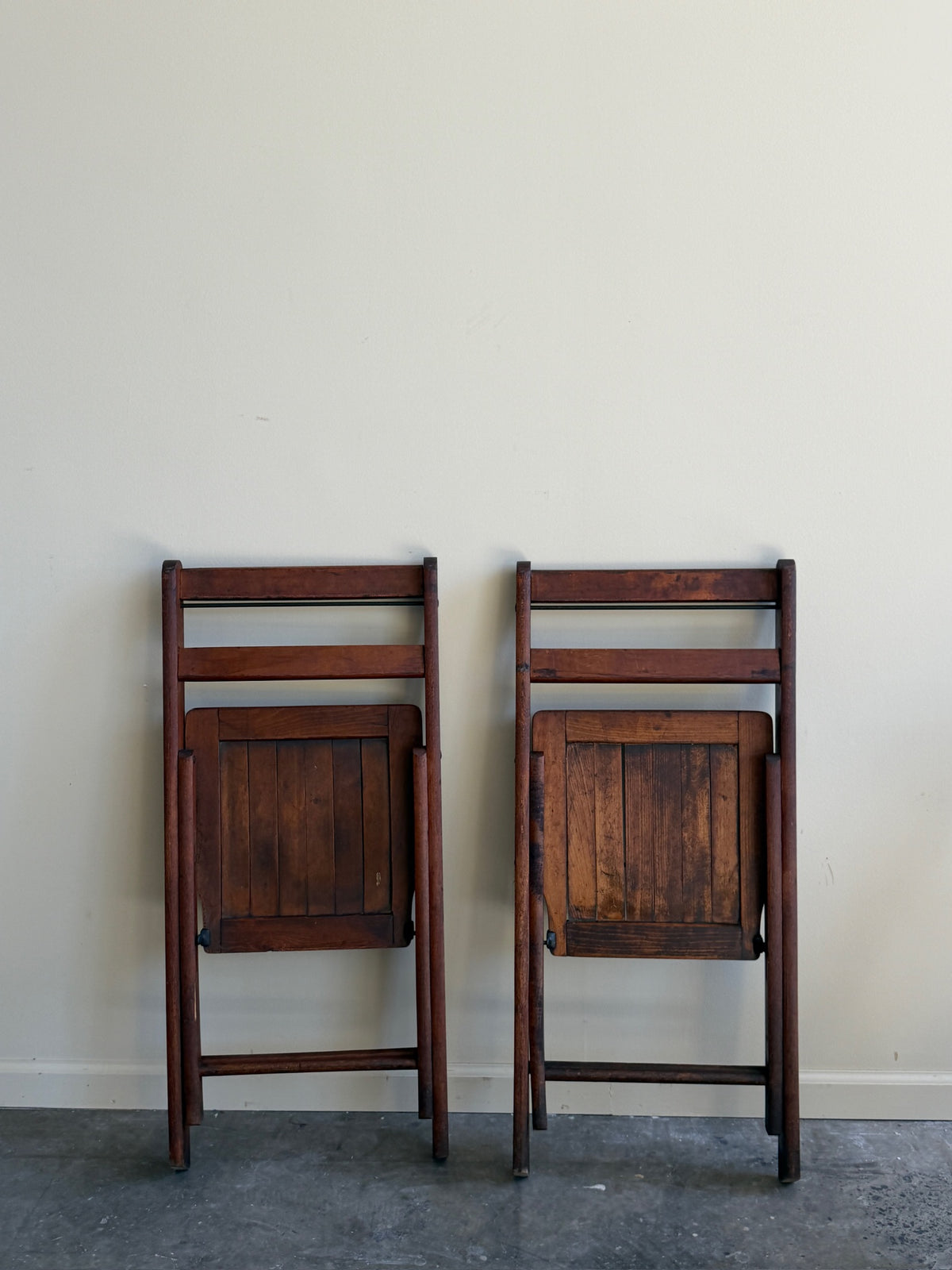 Stained pine folding chairs. Sold as a pair.