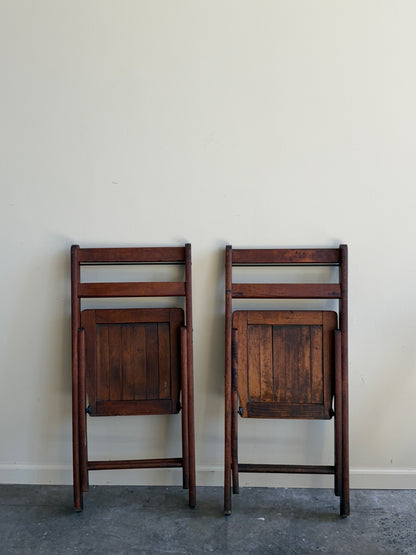 Stained pine folding chairs. Sold as a pair.