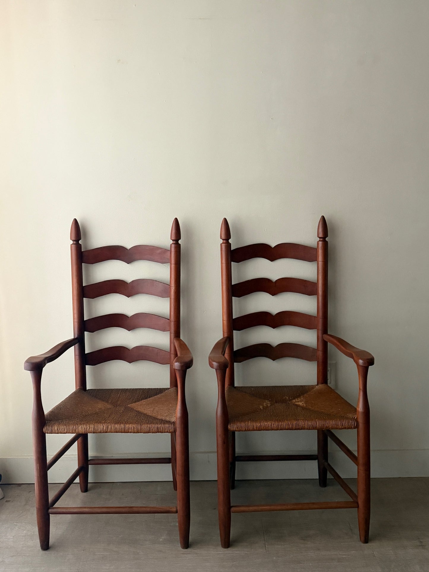 Cherry ladder back rush seat chairs with arms. Sold individually.