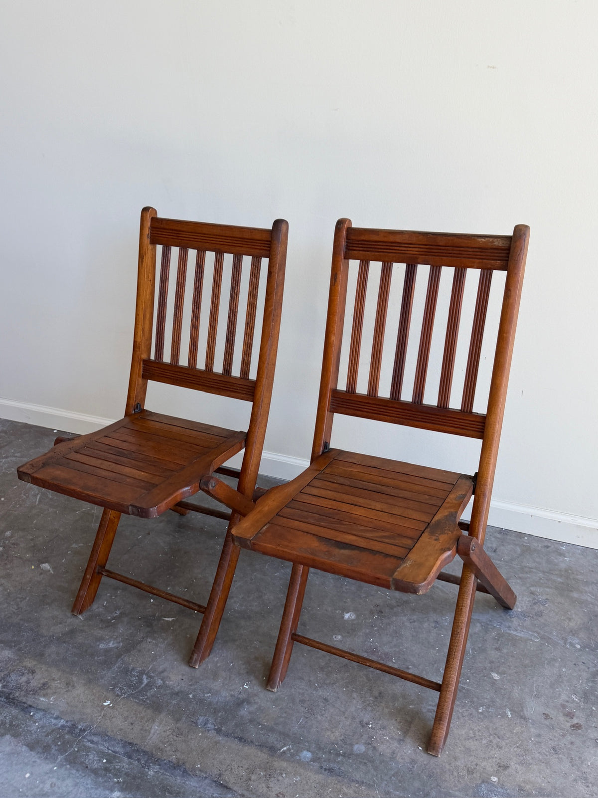 Stained pine folding chairs. Sold as a pair.