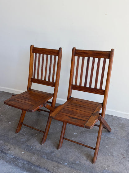 Stained pine folding chairs. Sold as a pair.