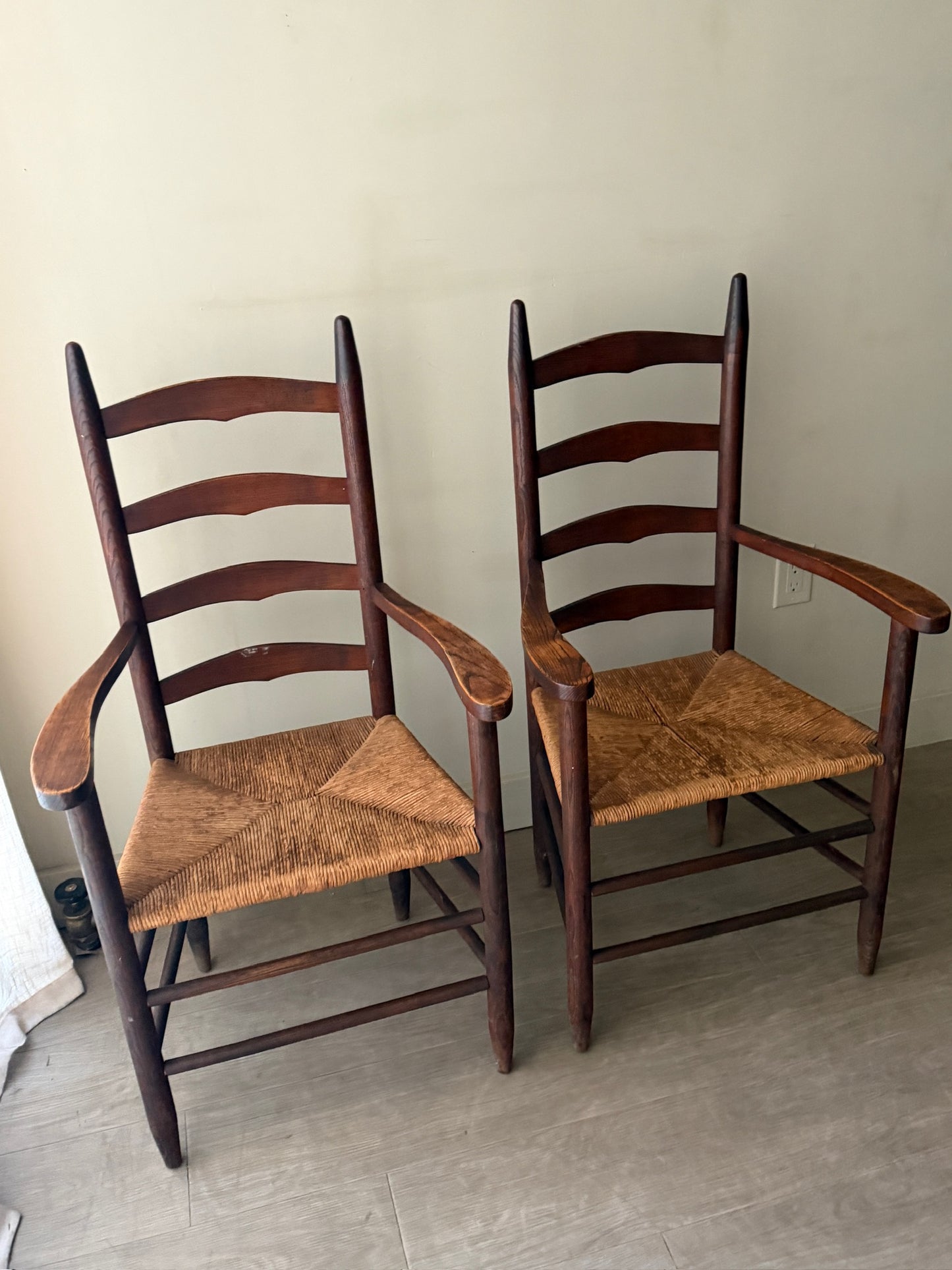 Oak ladder back rush seat dining chairs with arms. Sold as a pair.
