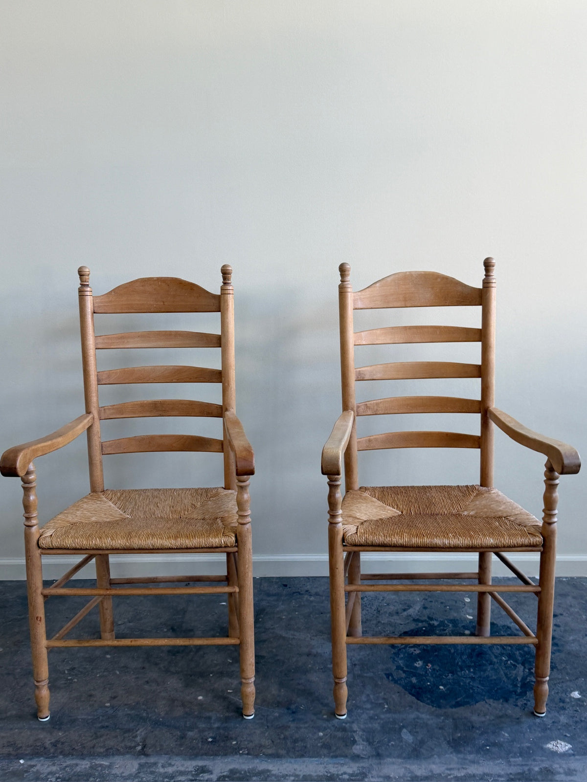 Beech ladder back rush seat arm chairs. Sold individually.