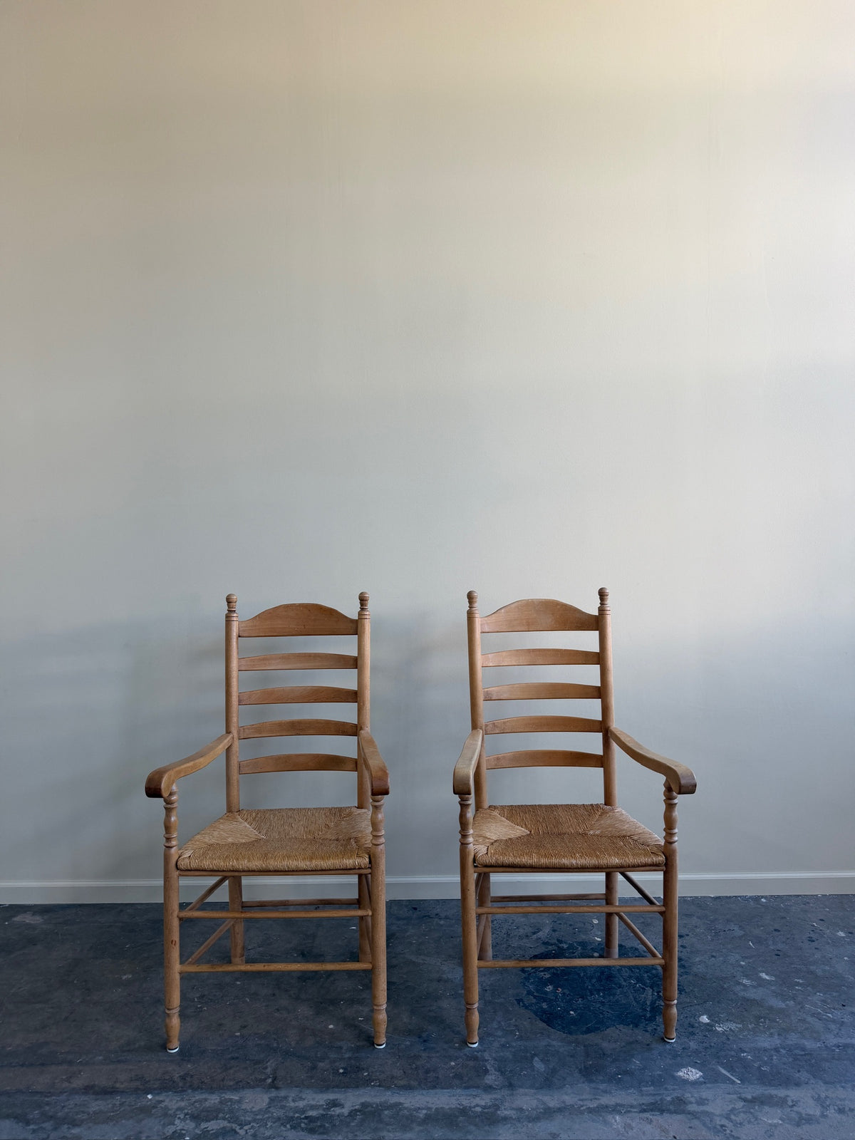 Beech ladder back rush seat arm chairs. Sold individually.