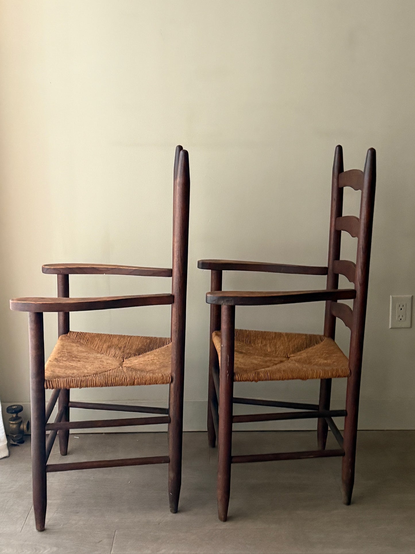 Oak ladder back rush seat dining chairs with arms. Sold as a pair.