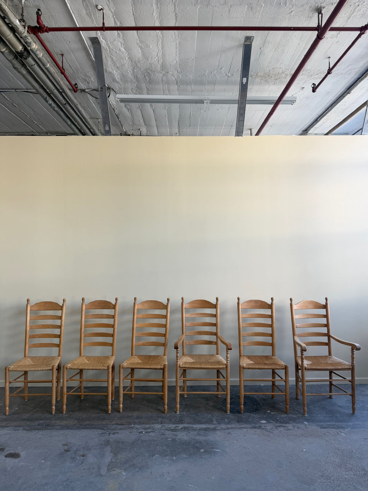 Beech ladder back rush seat arm chairs. Sold individually.