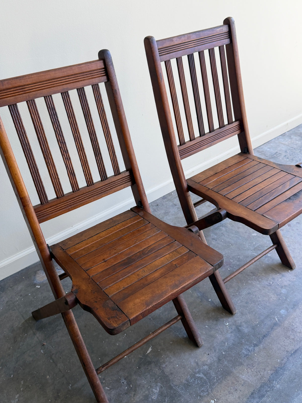 Stained pine folding chairs. Sold as a pair.