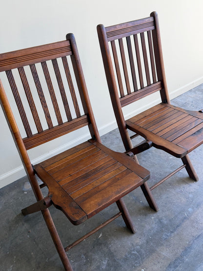Stained pine folding chairs. Sold as a pair.