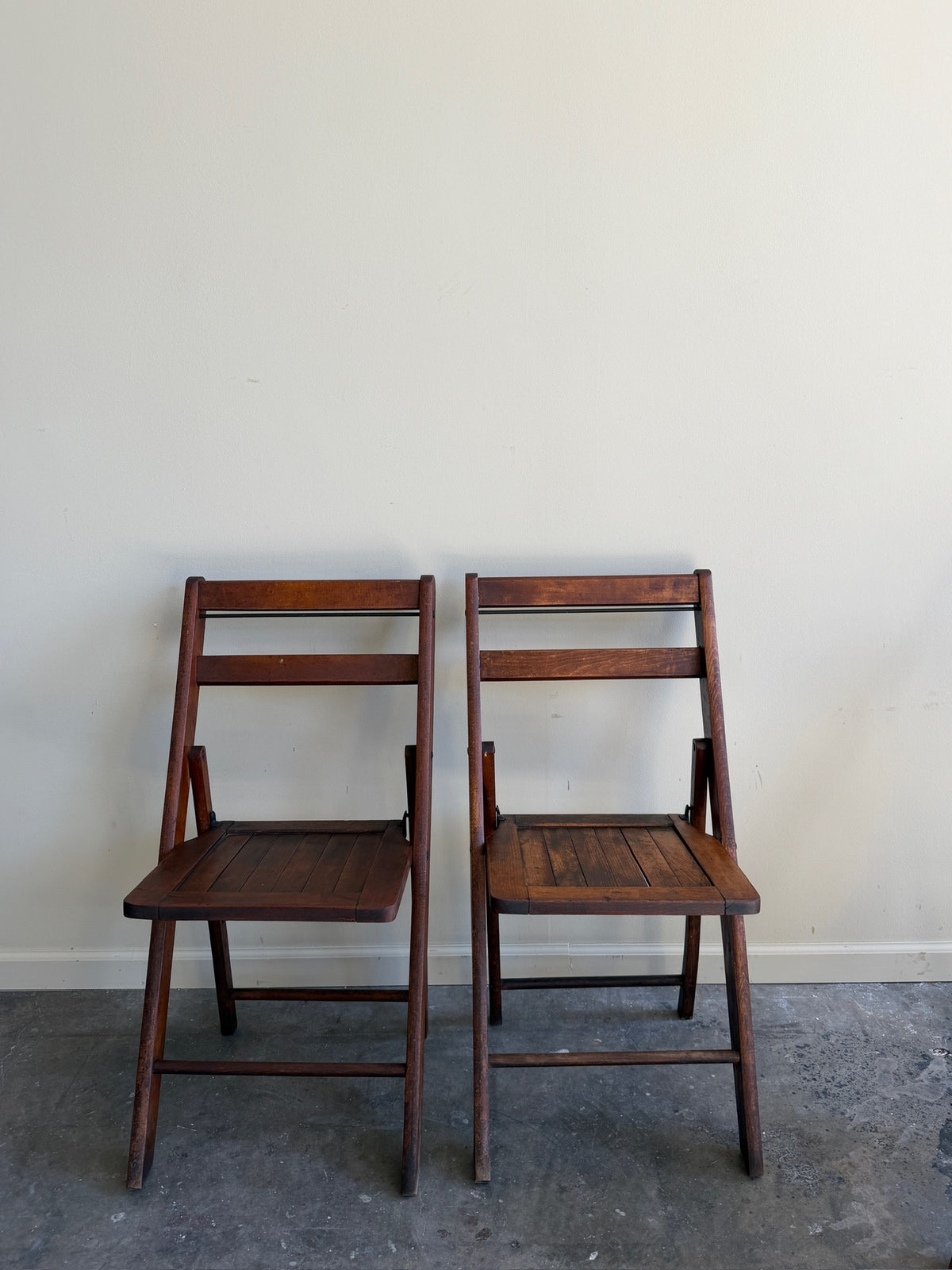 Stained pine folding chairs. Sold as a pair.