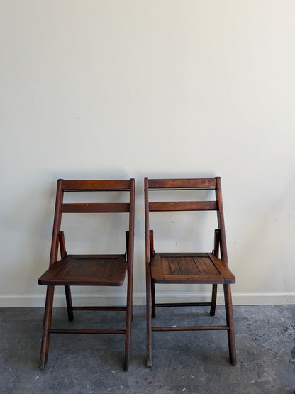 Stained pine folding chairs. Sold as a pair.
