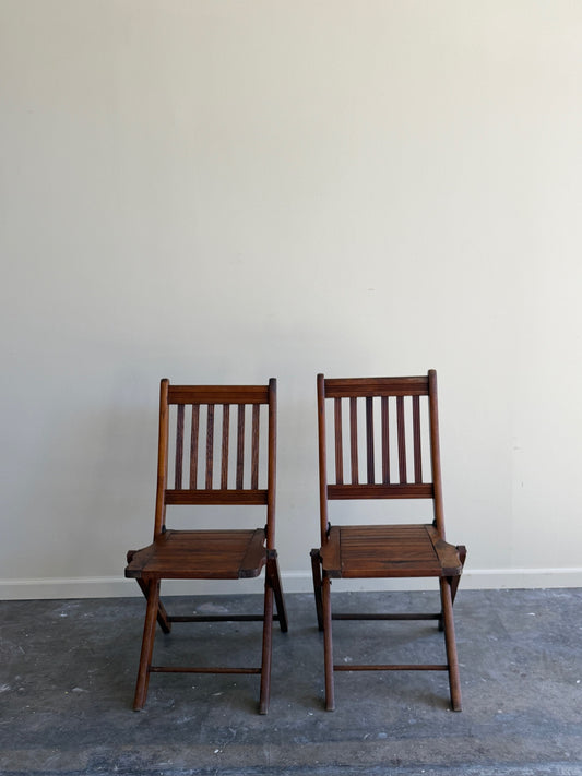 Stained pine folding chairs. Sold as a pair.
