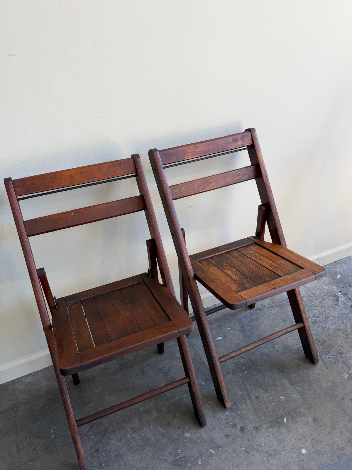 Stained pine folding chairs. Sold as a pair.