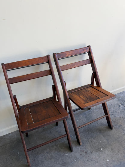 Stained pine folding chairs. Sold as a pair.