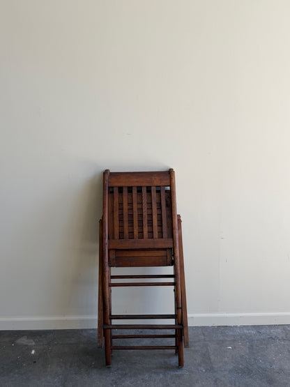 Stained pine folding chairs. Sold as a pair.