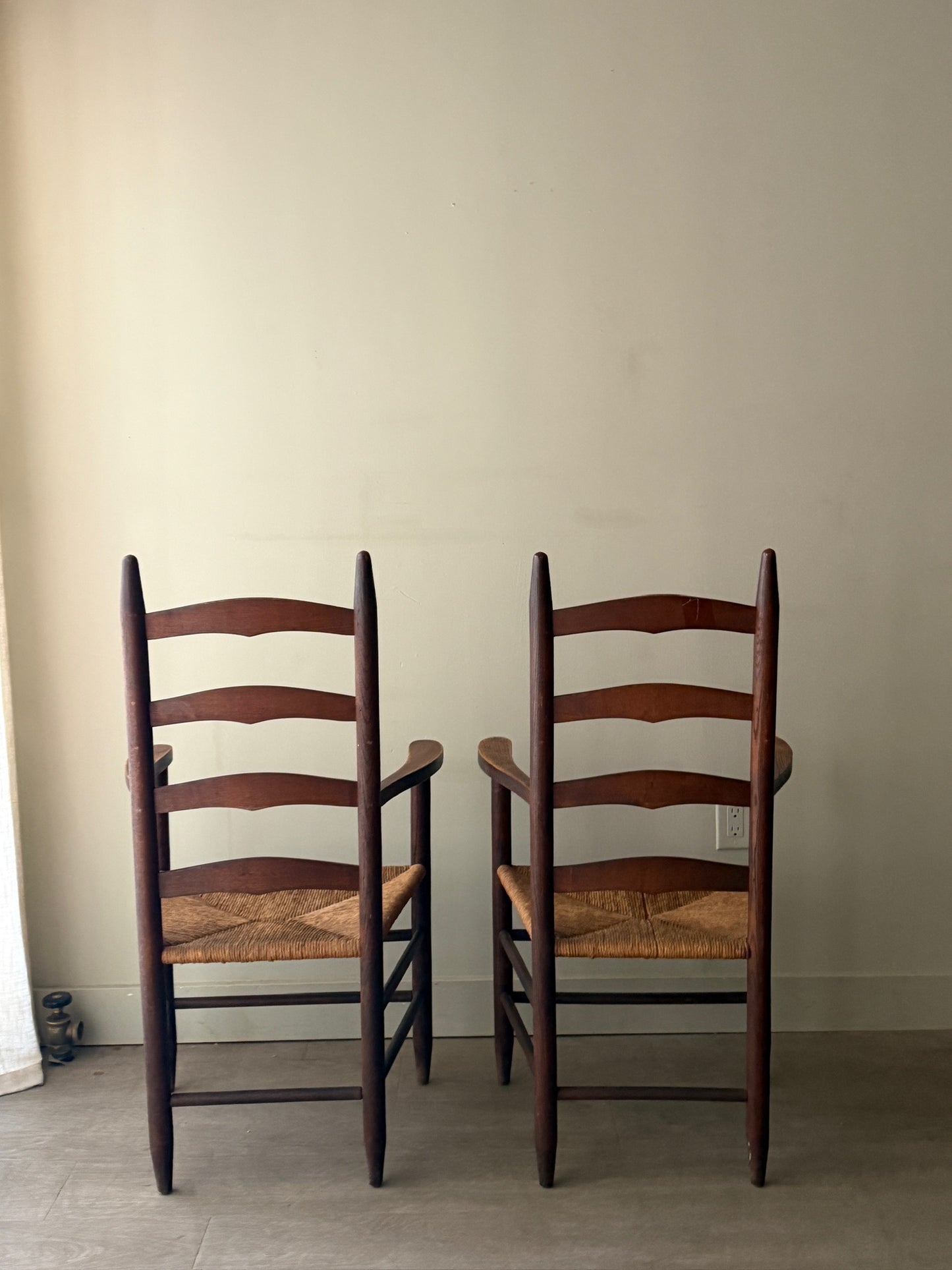 Oak ladder back rush seat dining chairs with arms. Sold as a pair.